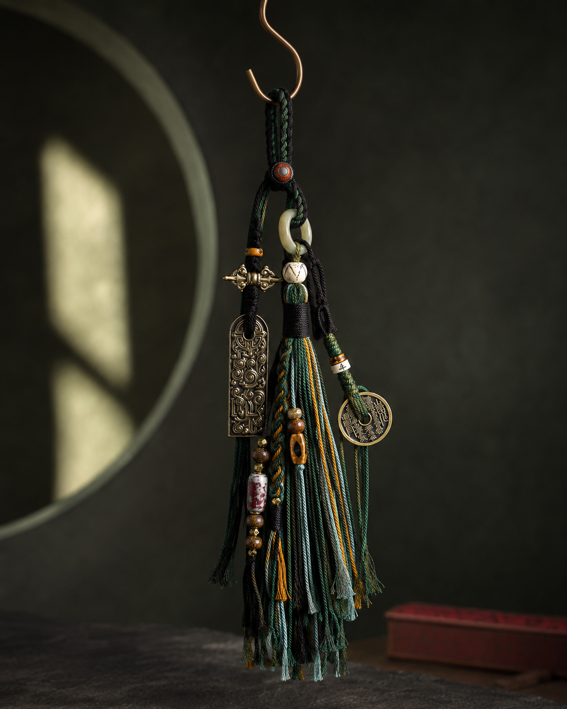 Forest tassel charm suspended against a dark green architectural background.